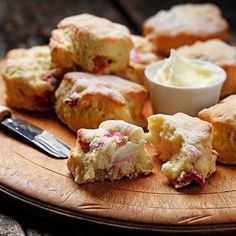 a wooden plate topped with scones and butter