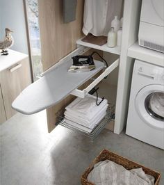 an ironing board is sitting on top of a shelf next to a washer and dryer