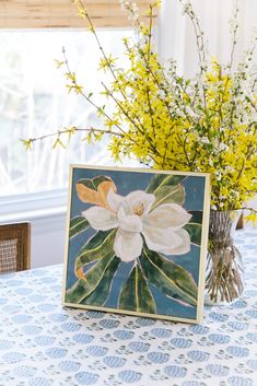 a vase filled with yellow flowers sitting on top of a blue table cloth covered table