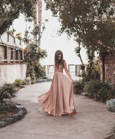 a woman in a long dress walking down a path