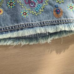 an old pair of jeans with colorful embroidered designs on the side and fringed edges