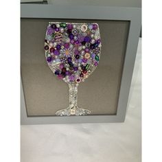 a wine glass made out of beads and other items in a shadow box on a table