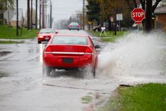 a red car driving through a flooded street