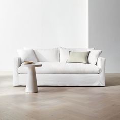 a white couch sitting on top of a hard wood floor next to a table and chair