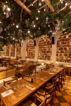 a restaurant with wooden tables and chairs covered in bookshelves filled with wine bottles