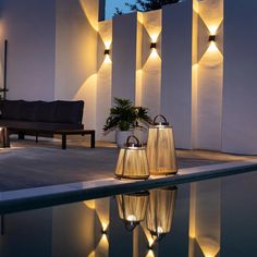 two lamps sitting on top of a pool next to a wall with lights in it