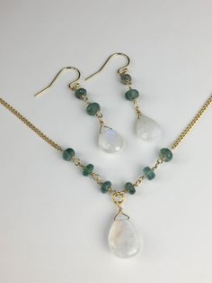 Emerald Moonstone Necklace Set Dangle Moonstone Jewelry With Gemstone Accents, Moonstone Dangle Earrings With Gemstone Accents, Moonstone Gemstone Beads Pendant Jewelry, Moonstone Pendant With Gemstone Beads, Elegant Moonstone Gemstone Beads Jewelry, Moonstone Necklaces With Gemstone Accents, Gold Moonstone Jewelry With Stones, Round Moonstone Necklace With Gemstone Accents, Elegant Moon Shaped Jewelry With Natural Stones