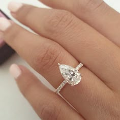 a woman's hand with a diamond ring on top of her finger and an engagement band