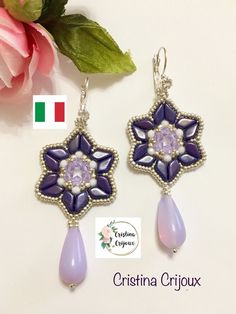 the earrings are decorated with purple beads and glass drops, along with a pink flower