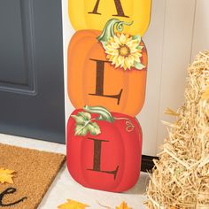 pumpkins are stacked on top of each other in front of a door with fall decorations