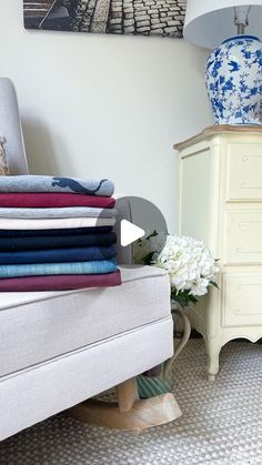 a stack of folded towels sitting on top of a bed next to a white dresser