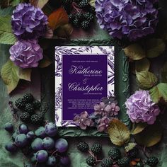 a wedding card surrounded by purple flowers and blackberries on a green background with leaves