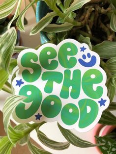 a green sticker that says see the good on it next to a potted plant