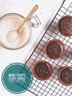 chocolate cupcakes on a cooling rack with a spoon next to it and a jar of powdered sugar in the background