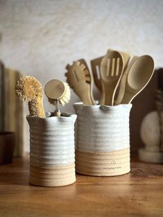 two ceramic cups with spoons and spatulas in them