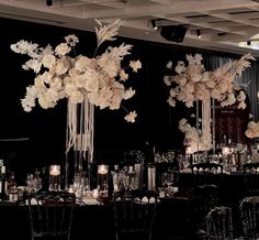 an elegant wedding setup with tall centerpieces and flowers on the tables in front of black drapes