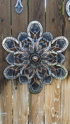 an intricate metal wall hanging on a wooden fence