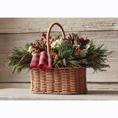 a wicker basket filled with pine cones and greenery on top of a table