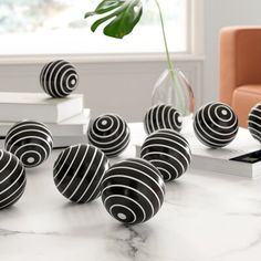 several black and white balls sitting on top of a table next to a plant in a vase