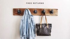 a denim jacket hanging on a wall next to a purse and coat rack with hooks