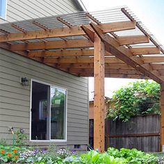 an outdoor patio covered with wooden pergols and plants in front of a house