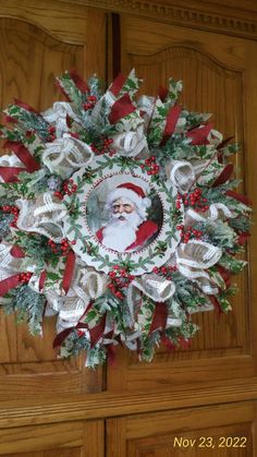 a wreath with santa claus on it is hanging on the front door, decorated with red and white ribbon