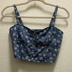 Brand New With Tags! Blue, Denim-Looking Crop Top With Purple Flowers. Excellent Condition - With Tags And Never Worn. The Straps Are Adjustable And The Back Is Elastic, Allowing For The Perfect Fit! The Buttons Along The Front Are Pearl-Like. The Last Photo Shows The Top Inside Out! Please Message Me With Any Questions Or Offers! :) Cute Denim Blue Cotton Tops, Spring Denim Blue Cotton Crop Top, Cute Cotton Crop Top With Floral Print, Cute Cotton Floral Print Crop Top, Denim Blue Cotton Crop Top For Spring, Trendy Cotton Floral Print Crop Top, Casual Denim Blue Crop Top For Summer, Cute Blue Crop Top For Summer, Cute Summer Denim Tops