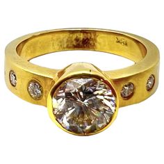 a yellow gold ring with a diamond in the center and two diamonds on each side