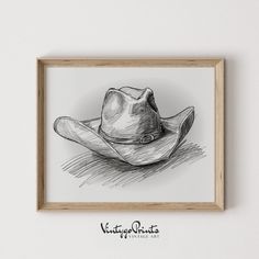 a black and white drawing of a cowboy hat on a wall above a wooden frame