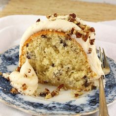 a piece of cake with white frosting and nuts on it sitting on a plate