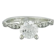 a white gold ring with an oval cut diamond in the center and pave set shoulders