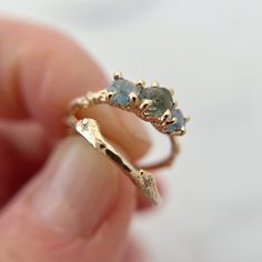 a close up of a person holding a gold ring with two blue stones on it