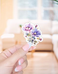 a person holding up a sticker with flowers on it in front of a couch