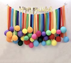 colorful streamers and balloons are hanging on the wall with happy birthday written above them