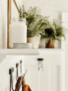 a shelf filled with plates and cups next to a candle on top of a counter