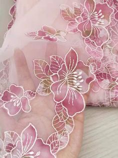 the pink and white flowers are embroidered on this sheered fabric, which is very delicate