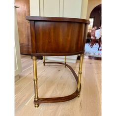 a wooden table with brass legs and a wood top on the floor in a living room