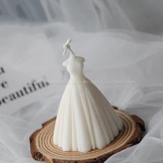 a small white dress on top of a wooden slice in the shape of a mannequin