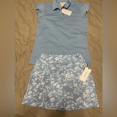 Nwt. Smoke Free Home. Both Pieces Have Upf 50 Uv Protection. Size Small Blue Polo With Zipper At Neckline And Dainty Flutter Sleeves. Size Xs Skort With A Wide Waistband, 2 Side Pockets And A Zippered Back Pocket. 14.25” Length Of Skirt. 3” Inseam Of Spandex Shorts. Polyester/Spandex Blend. Spring Cotton Sports Skort, Fitted Cotton Skort In Athleisure Style, Fitted Cotton Athleisure Skort, Fitted Cotton Skort For Athleisure, Cotton Athleisure Fitted Skort, Fitted Cotton Skort For Sports, Sporty Cotton Fitted Tennis Skirt, Casual Fitted Golf Shorts, Fitted Blue Shorts For Tennis