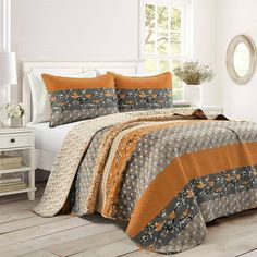 a bed with orange and gray bedspreads in a room