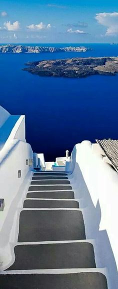 stairs leading up to the top of a white building with blue water in the background