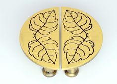 two brass colored leaves on each side of the door knobs are engraved with black ink