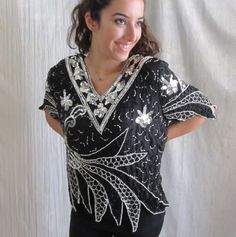 "Straight from the era of disco, this fab little top has so much going on. All over sequins and beads in black and silver. Check out the zig zag design at the bottom and sleeves. 100% silk. Made in India. EXCELLENT vintage condition with no spots, holes or other defects. All sequins appear to be intact. As with all pre-owned clothing, this should be laundered prior to wearing. FITS SIZE M-L Please review the measurements below for an accurate fit. All measurements are taken with the garment laid Black Party Top With Contrast Sequin, Black Party Tops With Contrast Sequin, Black Contrast Sequin Tops For Party Season, Silver Sequin Tops For Evening, Retro V-neck Party Tops, Disco Style Top For Evening Party Season, Black Tops For Festive Party Season, Black Sequin Disco Top, Black Sequined Disco Top