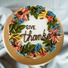 a decorated cake with the words give thanks written in frosting and flowers on it