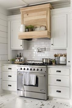 a stove top oven sitting inside of a kitchen next to white cupboards and drawers