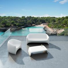 a white couch sitting on top of a roof next to a body of water with trees in the background