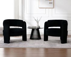 two black chairs sitting next to each other on top of a hard wood floor in front of a white wall