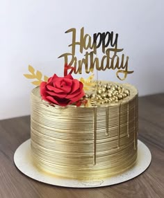 a gold birthday cake with a red rose on top