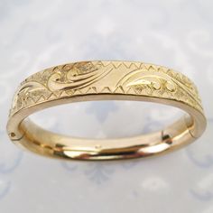 "A wonderful engraved design tops this vintage 10k gold filled oval bangle bracelet. The bracelet has a dense weight and thick heavy gold finish. Gold swirls and a circular pattern flows across the bracelet with the small central surface plain and shiny (meant for a monogram). The back of the bracelet is also plain. The 7/16 inch wide bracelet has an oval curvy shape. The sturdy form is nice and smooth with no major dings. The bracelet opens with a tiny push-button and closes securely. The inside is signed \"EJC\" on one side and hallmarked, \"10K Gold Shell (gold filled)\" on the other. The bracelet tested as gold filled and the total inner circumference of the bangle measures approx.  6 5/8 inches. It is in very good vintage condition with expected surface wear as pictured. There is an i Antique 14k Stamped Bangle As Gift, Vintage Yellow Gold Bangle Stamped 14k, Classic Gold Cuff Bracelet With Intricate Design, 14k Gold Bangle Bracelet With Intricate Design, 14k Gold Bangle With Intricate Design For Anniversary, Anniversary 14k Gold Bangle With Intricate Design, Victorian Gold Bangle Bracelet With Intricate Design, Ornate Engraved Gold Bangle Bracelet, Victorian Gold Bracelet With Intricate Design