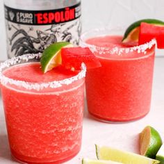 two glasses filled with watermelon margaritas next to a bottle of tequila and lime